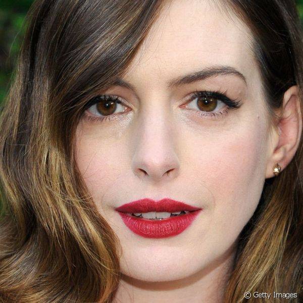 Anne Hathaway escolheu uma das combinações de make mais clássicas e elegantes: batom vermelho opaco e olhos delineados de preto